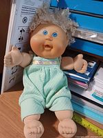 Full view of doll seated against shelf