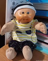 Full view of 12-inch Cabbage Patch Kids Preemie doll seated, showing outfit and hat