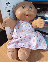Full view of 12" Cabbage Patch Kids Preemie doll seated on surface
