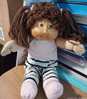 Full view of Cabbage Patch Kid doll seated showing outfit and size