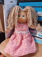 Full view of 16-inch Cabbage Patch Kids doll seated, showing dress and hair