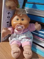 Full view of Cabbage Patch Kids Preemie doll sitting, showing outfit and pacifier