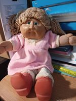 Full view of Cabbage Patch Kids doll seated on surface