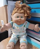 Full view of Cabbage Patch Kids doll seated, showing outfit and size