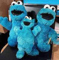 Group shot of three Cookie Monster plush figures