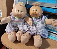 Front view of both 13" Cabbage Patch Kids twin dolls seated on table