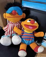 Both Ernie plush dolls side by side