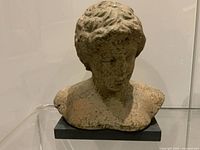 Front three-quarter view of terracotta bust on black stone base