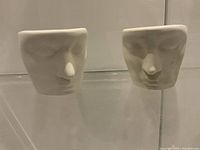 Front view of both white ceramic abstract face planters