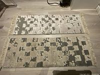 Two wool tufted mats displayed side by side on floor