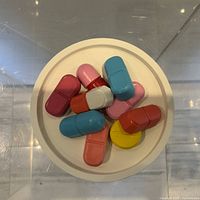 Top view of sculpture showing multicolored pill forms on white round base
