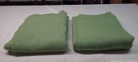 Two folded light green wool blankets on table