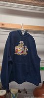 Front view of navy Disney hoodie on hanger showing embroidered Seven Dwarfs graphic and kangaroo pocket