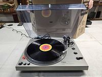 Turntable with dust cover open, spinning record visible