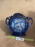 Front view showing flow blue floral design, gold trim and two handles