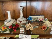 Shelf with two floral porcelain decanters, multiple china flower ornaments and small porcelain pieces