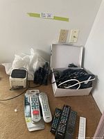 Overall lot with Sony clock radio, headphone base, bag, box of cables and remotes on carpet