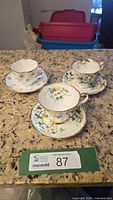 All three floral cup and saucer sets on counter