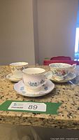 Three teacup and saucer sets displayed on countertop