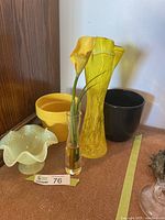 Group shot of all items: yellow crackle vase, opalescent bowl, bud vase with lily, yellow and black planters