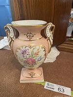 Full view of one Limoges vase showing pink ground, floral panel, swan handles, square base