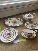 Group view of five visible pieces: teapot, oval platter, cake plate, gravy boat with underplate
