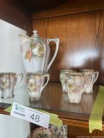 Chocolate pitcher and five cups displayed on shelf