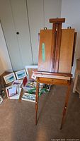 Overall view of wooden easel with frames and supplies on floor