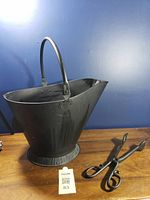 Coal scuttle bucket with handle and tongs beside it