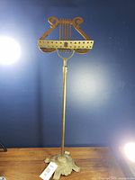 Full view of brass lyre-motif sheet music stand showing music rest, pole and base