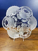 Front view of pressed glass platter showing crab and shell motif
