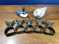 Group view of five cast-iron bird napkin rings, porcelain bird pomander, and ceramic loon