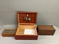 All three wooden boxes displayed; humidor open showing interior components, other two boxes closed