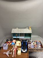 Overall view of lot with toys, cards, dollhouse, vehicle, figurines and box of sports cards