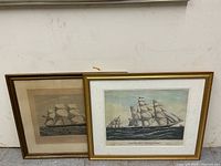 Both framed ship prints leaning against wall
