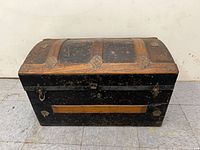Front view of dome top trunk displaying latches, wood slats and metal hardware
