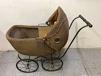 Side view of rattan stroller showing body, wheels and handle