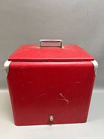 Front view of red metal cooler showing drain plug