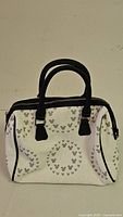 Front view of white Mickey Mouse embossed satchel with black handles