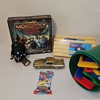 All items together: board game, toy, die-cast car, domino racks, bristle blocks tub, Pokémon pack
