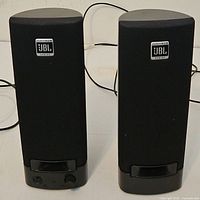 Front view of both JBL speakers showing grills, logos, volume knob and indicator