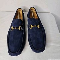 Top view of both navy suede loafers showing gold bit hardware