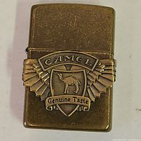 Front view showing Camel Genuine Taste wing badge on brass Zippo