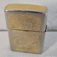 Front view of gold plated Camel Zippo lighter with engraved scrollwork and logo