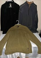 Three fleece pullovers laid out (black, charcoal, olive)