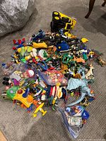 Wide view of entire pile of assorted plastic toys on carpet