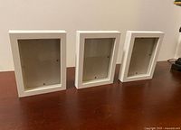 Front angled view of three white box frames