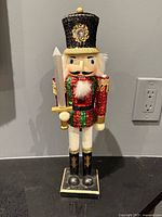 Front view of sequined wooden nutcracker with sword