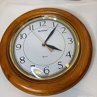Front view of wooden SkyTimer wall clock showing dial and hands