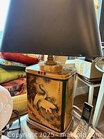 Tin lamp showing painted crane scene and black shade